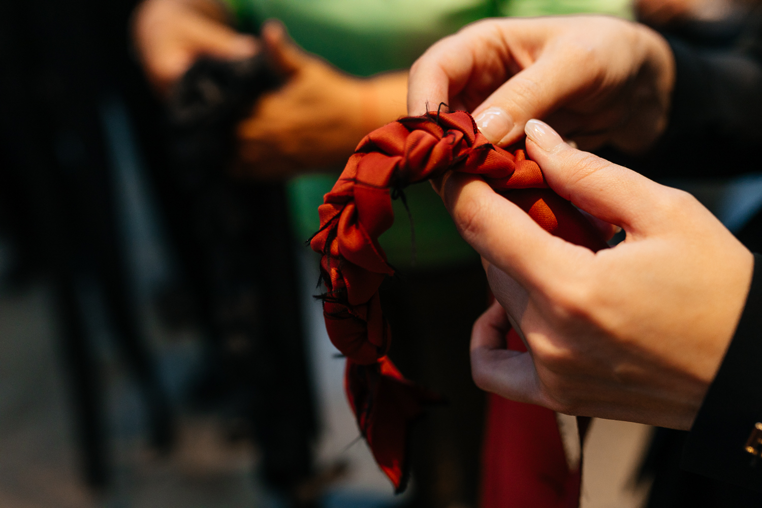 Hands weaving a red braid